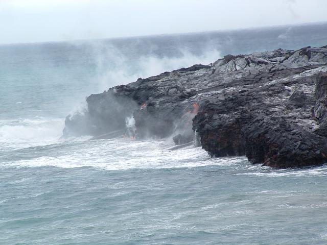 Red hot lava flows into the ocean and cools down forming new land.